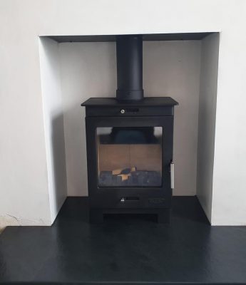 A Flavel Arundel black woodburning stove in a white surround with granite hearth