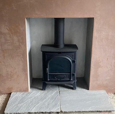 Sandstone flags hearth fitted to a woodburning stove in a plastered chimney breast.
