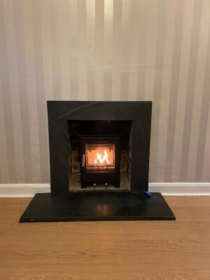 Woodburning stove fitted in a living room with grey striped wallpaper