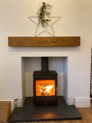 Fireplace with wooden mantlepiece fitted with woodburning stove by Sussex Woodburners