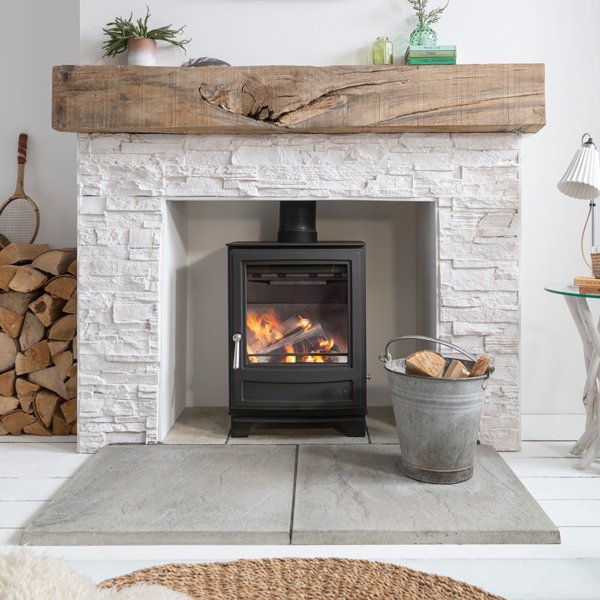 The Arada Ecoburn stove in a stylish stone fireplace with wood mantlepiece.
