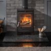 The Arada Hamlet Solution 5 multi-fuel stove shown in a fireplace with granite grate.