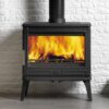 A Larchdale wood burning stove with a grey hearth and white painted wall behind.