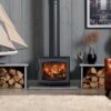The Wychwood wood burning stove shown in a contemporary living room with logs stored either side.