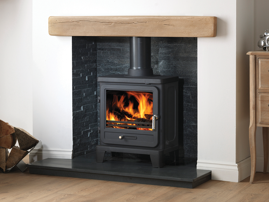 Capital Vega multi-fuel stove in a fireplace with white painted walls, grey interior and wooden mantlepiece.