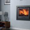 A Charlton & Jenrick FPi8 stove inset into a grey chimney breast in a living room with grey painted walls.