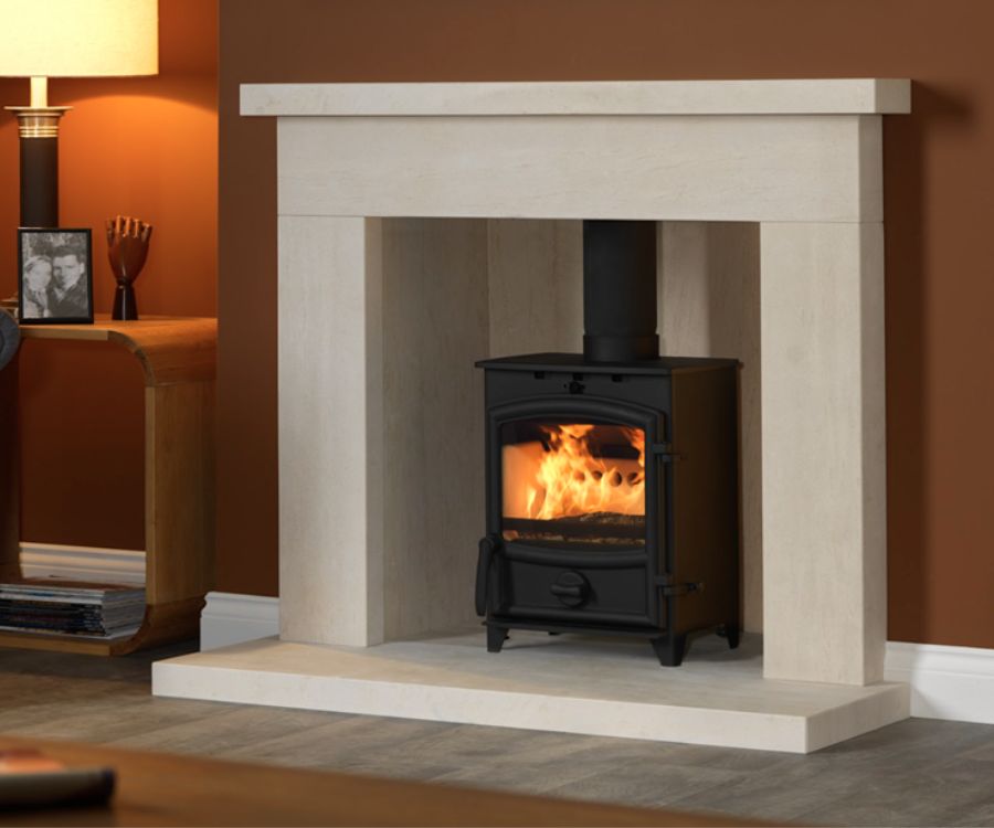 Fireline FX5 multi fuel stove in a traditional white stone fireplace with brown painted walls.