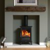 A Charlton & Jenrick Woodtec 5 Style wood burning stove set in a contemporary fireplace with oak mantle.