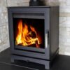 A Skiddaw wood-burning stove shown in a grey fireplace with logs burning inside.