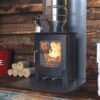 A Saltfire Scout stove in an inglenook fireplace with logs to the side