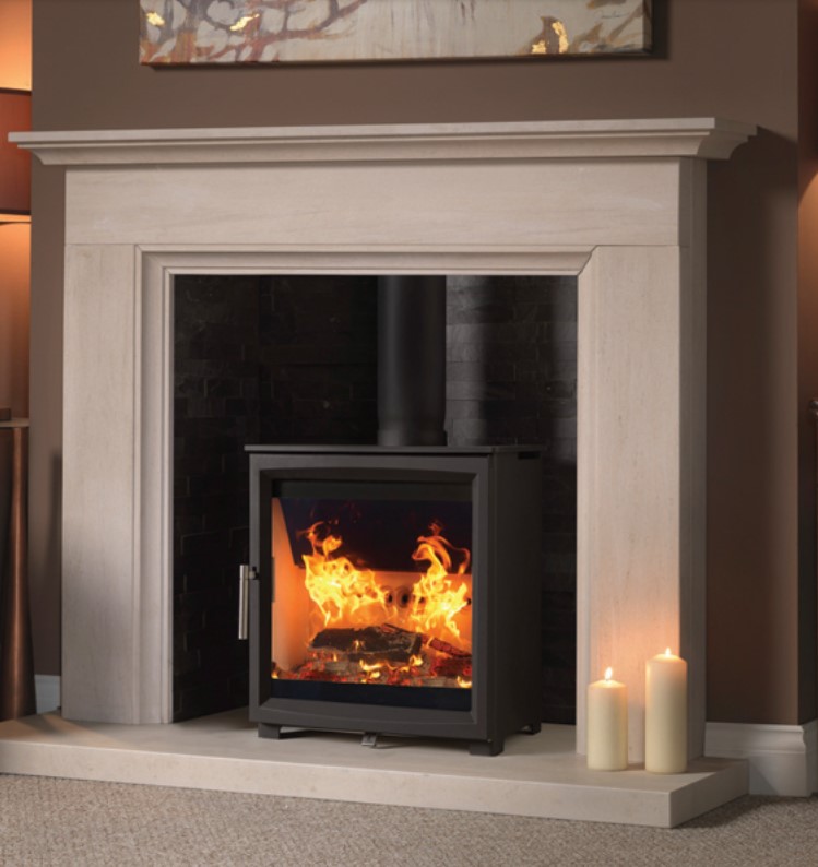 A Woodtec 5W wood-burning stove fitted in a traditional stone fireplace.