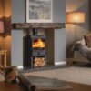A Charlton and Jenrick Fireline FX5W stove burning in the fireplace of a cosy living room. The stove has logs stored underneath and is fitted in a simple fireplace with a wood mantlepiece.