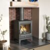 The F2 Vue Portrait woodburning stove shown in a fireplace with burning logs and brick hearth.