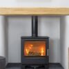 A Mendip Woodland multifuel stove burning in a white painted fireplace with wooden mantlepiece.