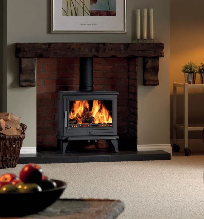 An ACR Rowandale multi-fuel stove shown alight in a cosy living room with a bowl of fruit in the foreground.