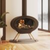 Contemporary oval wood burning stove with legs shown in a modern living space and wooden floor.