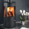 A cylindrical freestanding black wood-burning stove shown in a contemporary living room.