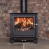 The Clock Blithfield multifuel stove shown in a fireplace with burning logs and brick hearth.