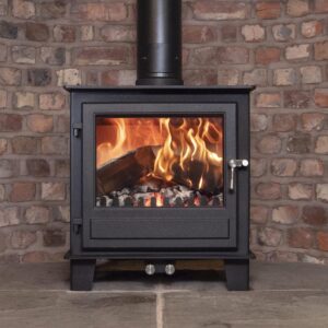 The Clock Blithfield multifuel stove shown in a fireplace with burning logs and brick hearth.