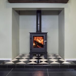 A compact multifuel stove shown in a chimney recess with wooden mantlepiece over.