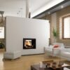 A woodburning stove which is set into a freestanding wall between two rooms so that the flames can be seen from both sides.